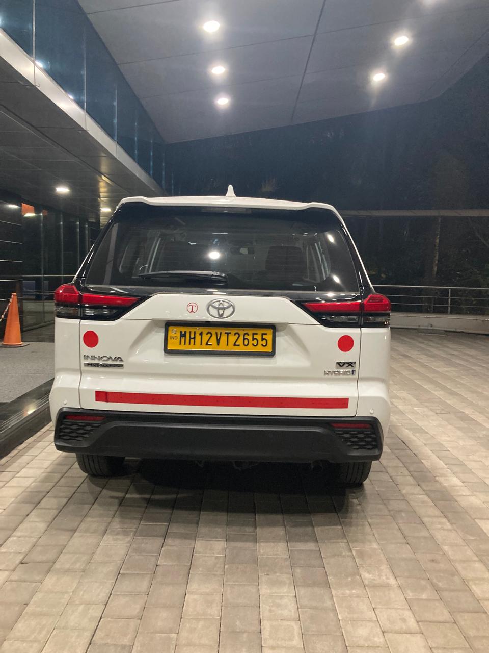 Om Travels Innova Hycross hybrid parked at a Pune hotel entrance
